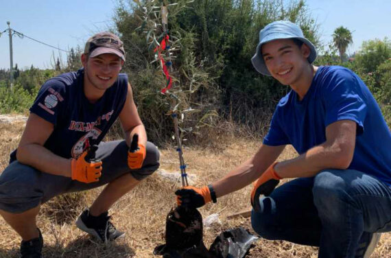 Two campers planting a tree.